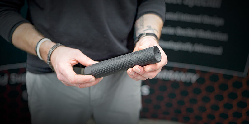 OGS-About-Us-24jpg Person holding an Off Grid Suppressors Trident TI titanium suppressor with a textured black finish, highlighting its lightweight design and precision-machined construction.